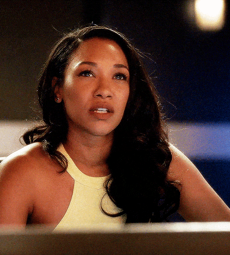 a woman with long dark hair is wearing a yellow tank top and earrings