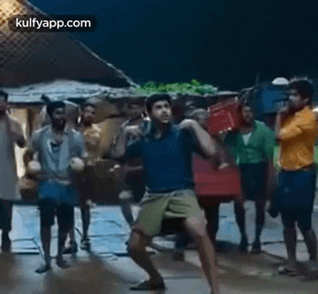 a man is dancing in front of a group of people while holding a box .