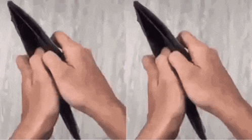 a person is holding an empty wallet in their hands and folding it in half .