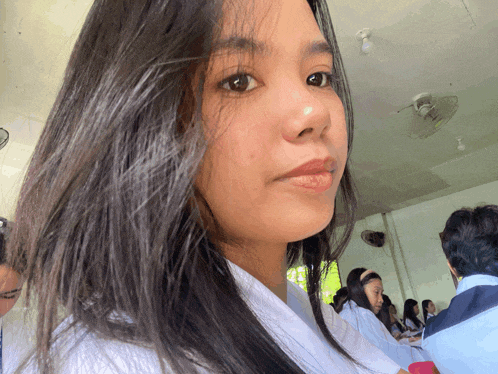 a girl with long dark hair is sitting in a classroom
