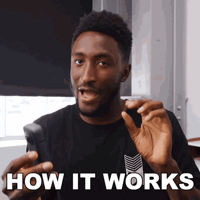 a man in a black shirt is holding a cell phone with the words how it works below him