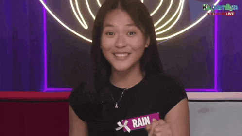a woman making a surprised face in front of a sign that says kapamilya