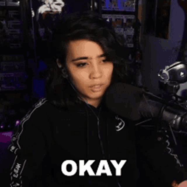 a woman sitting in front of a microphone with the word okay written on her face