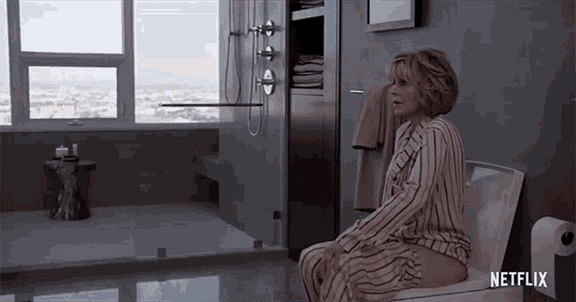 a woman sits on a toilet in a bathroom with a netflix logo in the corner