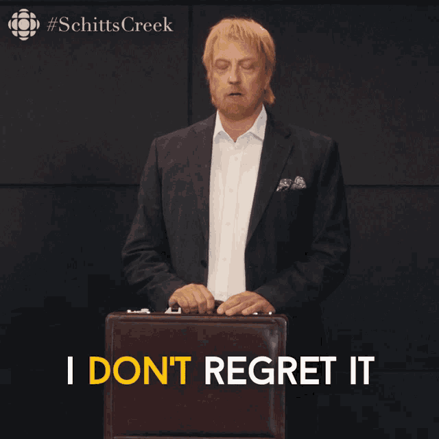 a man in a suit holds a briefcase and says i don t regret it