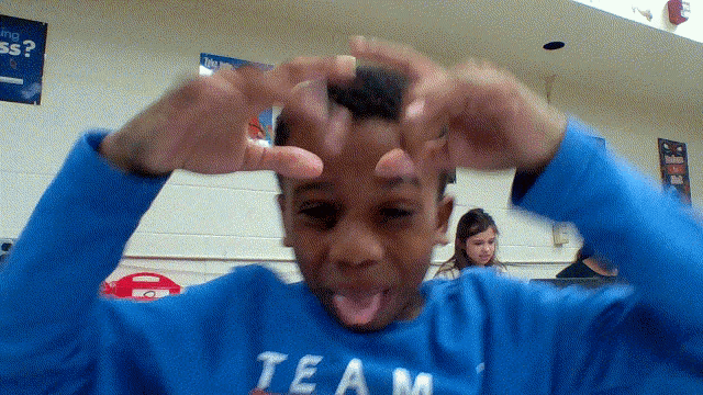 a young boy wearing a blue team shirt making a funny face