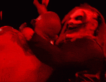 a man is holding another man 's arm in the air in a dark room .