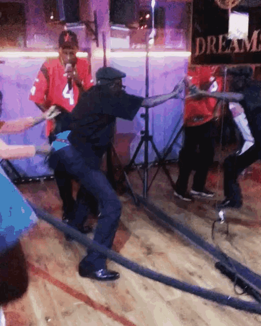 a group of people are dancing in front of a sign that says dream on it