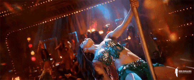a woman is dancing on a pole with the word red chillies on the bottom right