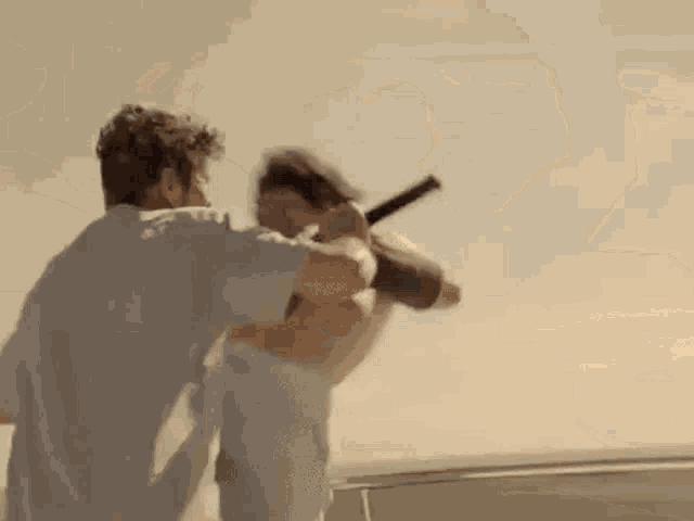 a man is riding a bicycle on a beach while another man is holding a sword .