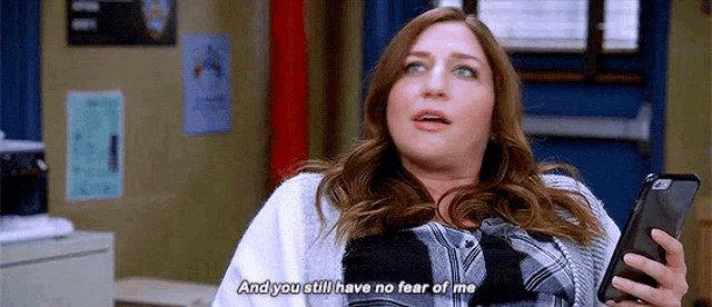 a woman is holding a cell phone and saying `` and you still have no fear of me `` .