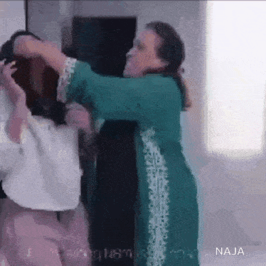 a woman in a green dress is holding another woman in her arms .