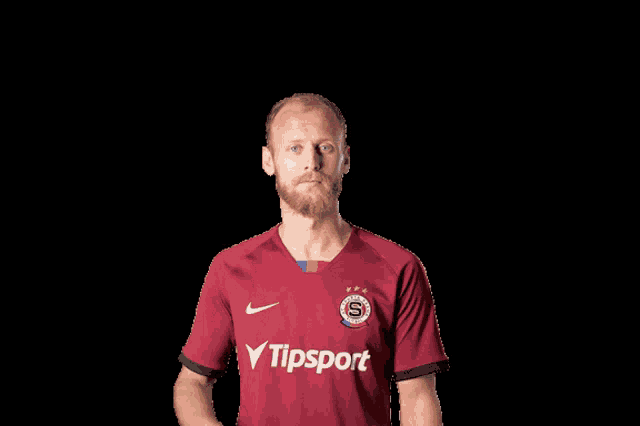 a man with a beard wears a red jersey with the word tipsport on it
