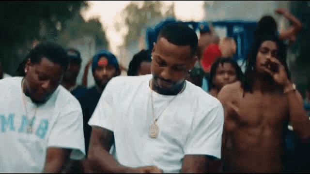 a man in a white shirt is standing in front of a group of men .