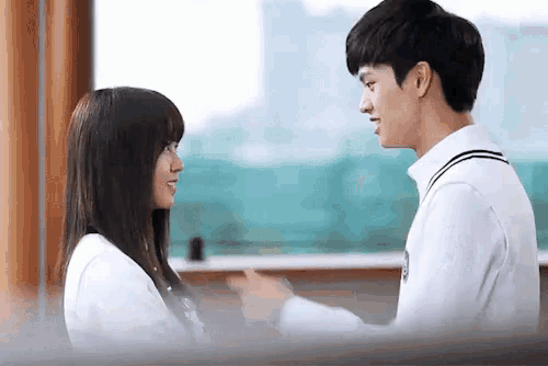 a boy and a girl are standing next to each other in a room .