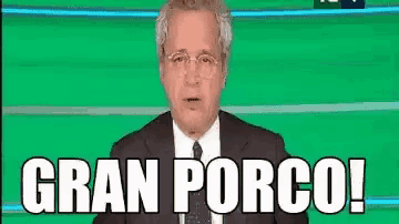 a man in a suit and tie is standing in front of a green screen with the words gran porco written on it .