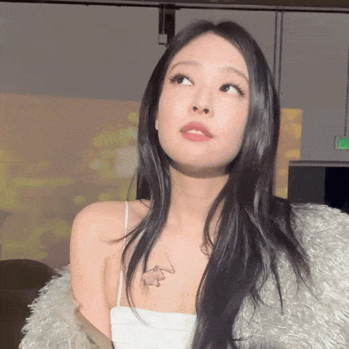 a woman with long black hair is wearing a white top and a fur coat