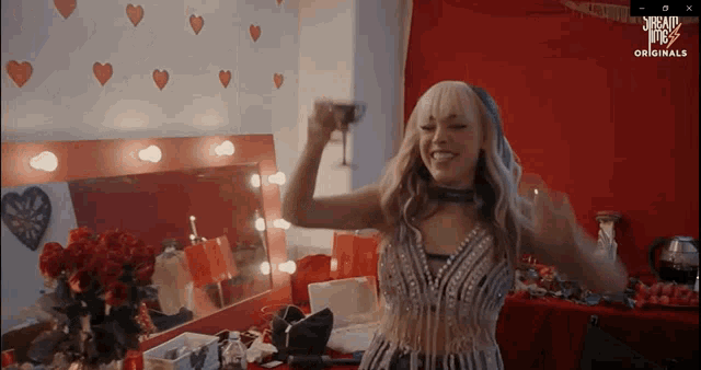 a woman is dancing in front of a mirror with hearts on the wall behind her and the word origin on the screen