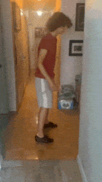 a man in a red shirt and white shorts standing in a hallway
