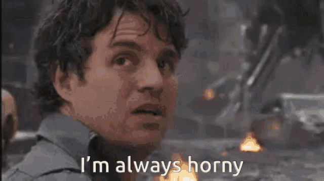 a man is sitting in front of a fire and says i 'm always horny