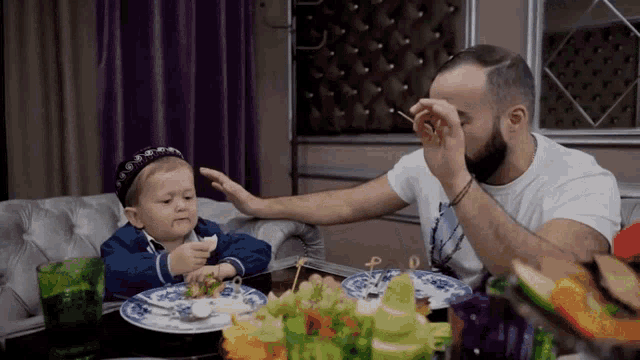 a man is feeding a baby a piece of food with a fork