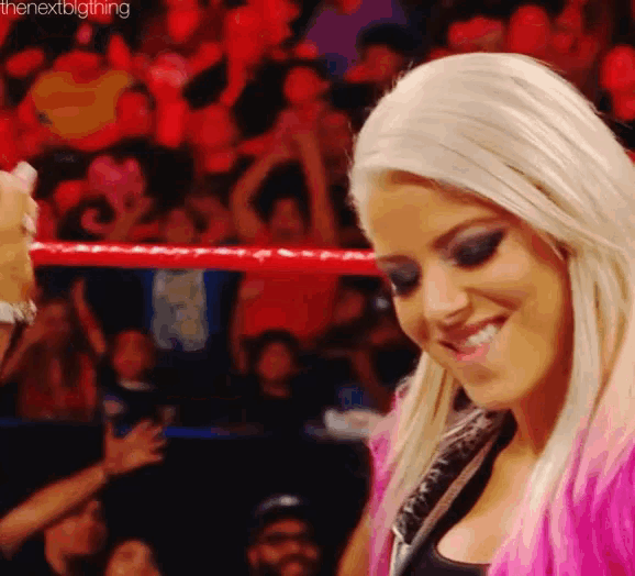 a woman is smiling in front of a crowd while standing in a ring .