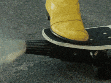 a person wearing yellow boots is riding a skateboard with smoke coming out of it