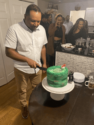 a man in a white shirt is cutting a cake