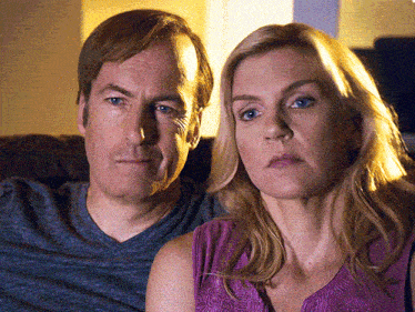 a man and a woman are sitting next to each other and the woman is wearing a purple top