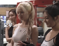a woman in a white tank top is standing next to two other women