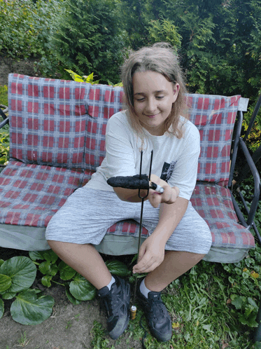 a young girl is sitting on a bench holding a tool