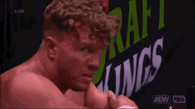 a wrestler is standing in front of a sign that says draft kings .