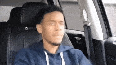 a young man is sitting in the back seat of a car .