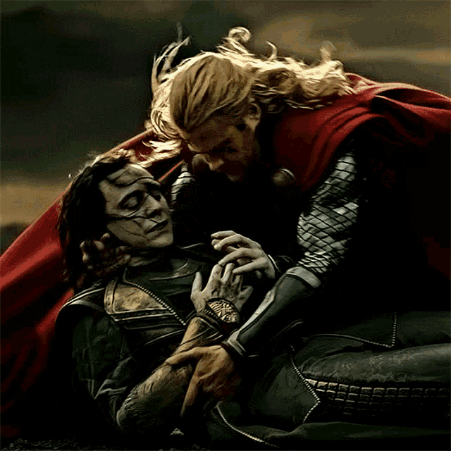 a man in a red cape is holding a man in a green suit