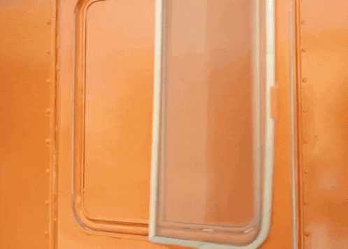 a man in a white t-shirt is standing in an orange room