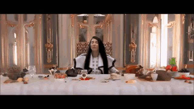 a woman sits at a table with a lot of food