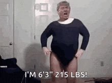 a man in a leotard is standing in a room with his hands on his hips .
