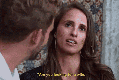 a man and a woman are looking at each other and the woman is asking the man if he is looking for a wife .