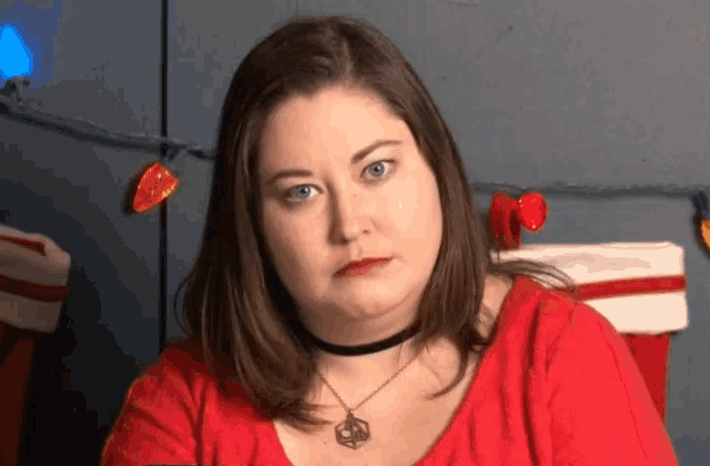 a woman wearing a choker necklace and a red sweater