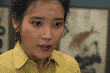 a close up of a woman 's face in front of a painting