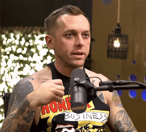 a man wearing a shirt that says business talks into a microphone