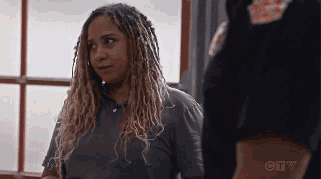 a woman with dreadlocks is standing next to a man in a black uniform .