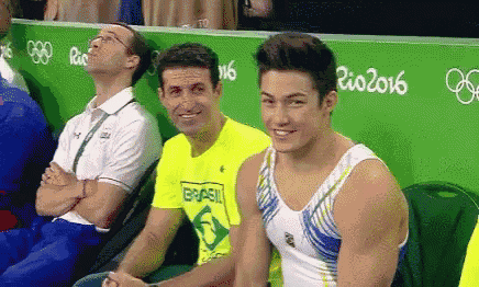 a man in a yellow shirt that says brasil is sitting next to another man in a white shirt .