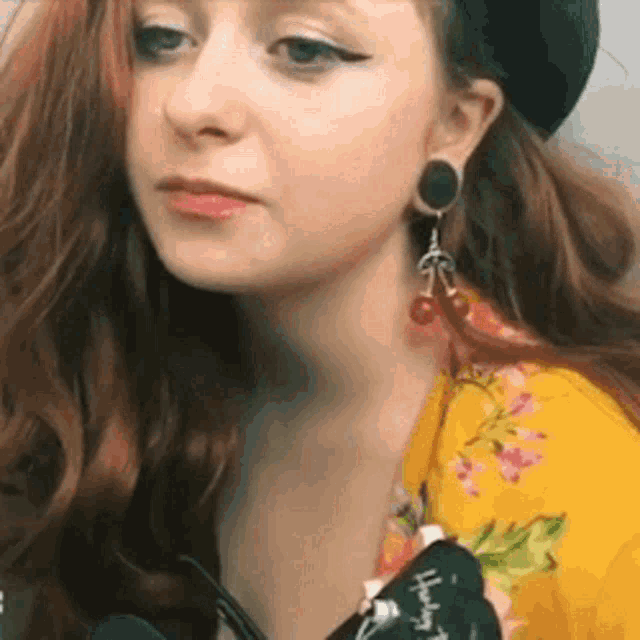 a close up of a woman wearing a yellow shirt and earrings .