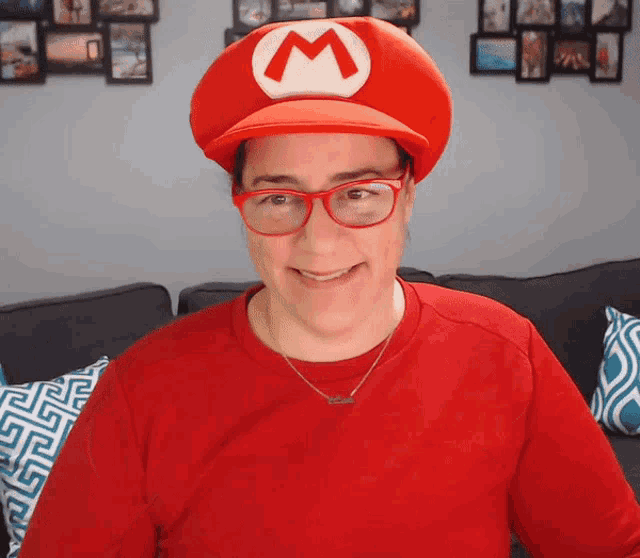 a woman wearing glasses and a red shirt is wearing a mario hat