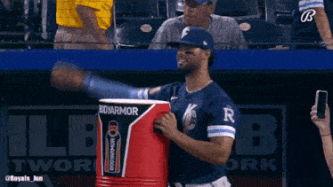 a baseball player is holding a bodyarmor cooler