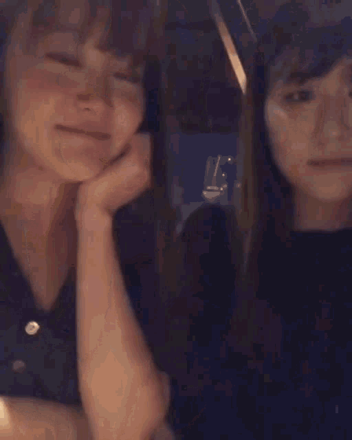 two women are standing next to each other and one of them is pointing at the camera