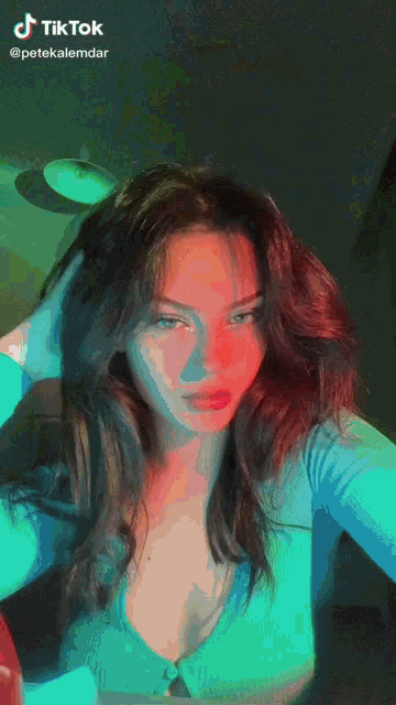 a woman in a blue shirt is taking a selfie with tiktok written at the bottom