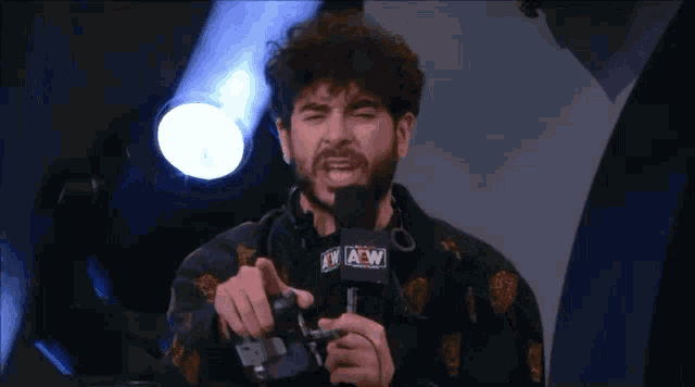 a man with a beard is holding a microphone in front of a microphone and making a funny face .