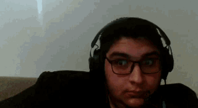 a man wearing glasses and headphones is sitting on a couch .